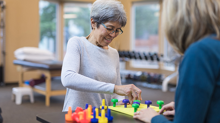 Older woman working with peg board with therapist
