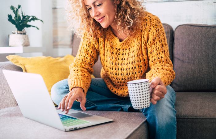 A woman sitting on a couch with a laptop.