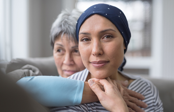 Young woman with cancer being comforted by her mother