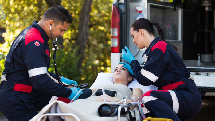 Emegency personnel monitoring woman on stretcher outside of ambulance