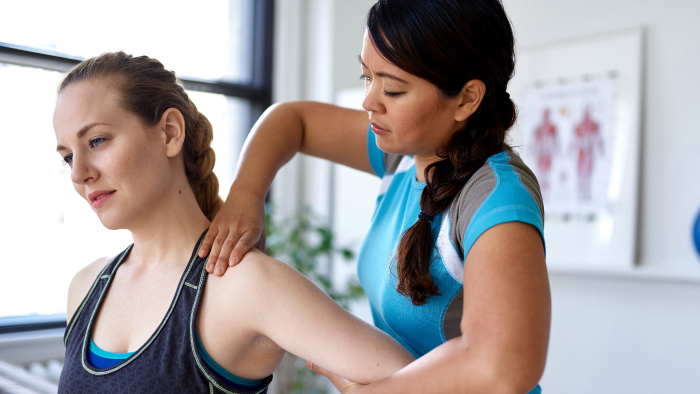 Physical therapist working shoulder of female patient