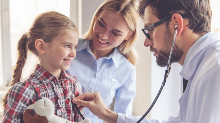 Doctor listening to young girl patient's heart