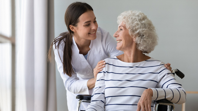 Young female nurse comforting woman in wheelchair