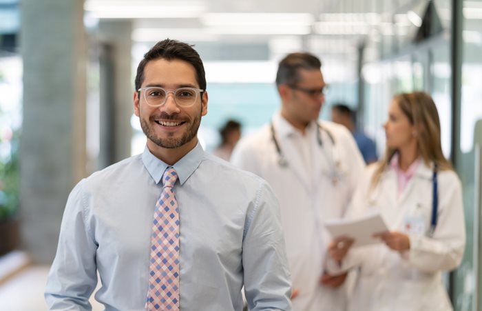 Young gentlemen in tie walking toward us with health care professionals blurred in background