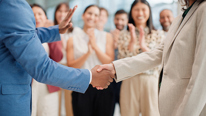 Handshake in front of colleague group to celebrate an accomplishment