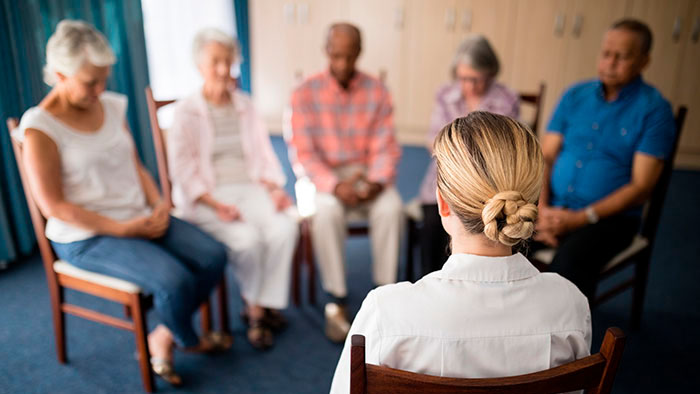Small group of people sitting in circle with heads bowed