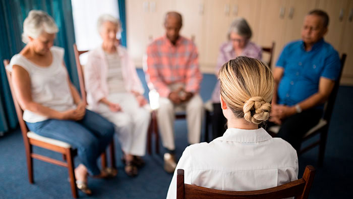 Small group of people sitting in circle with heads bowed