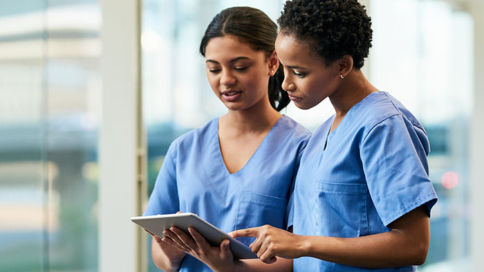 Two nurses consulting on a tablet