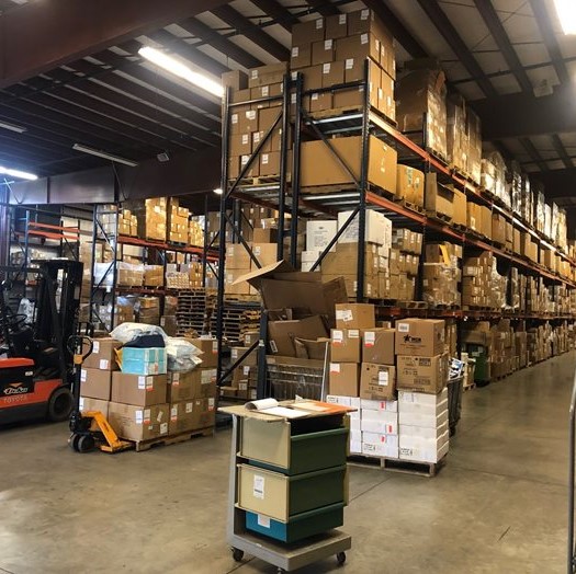 Boxes of donated items are stacked up to the ceiling in the large Mission Outreach warehouse