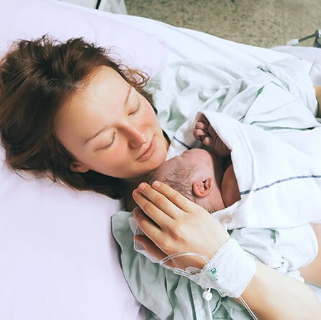 Mother laying in bed holding her new born baby