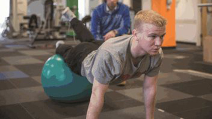 Young athlete doing physical therapy on balance ball