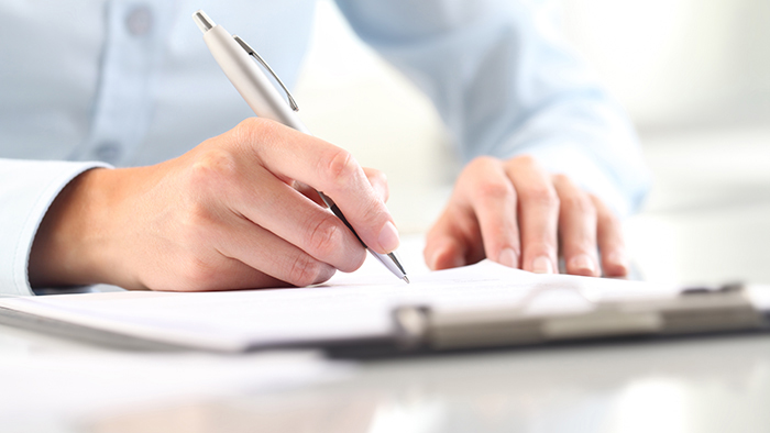 Hands filling out a form on a clipboard