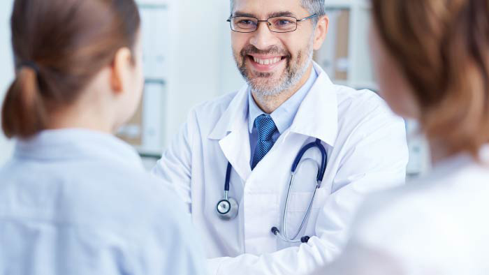 Male physician smiling with nurses