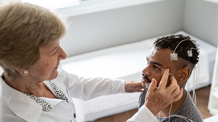 Female nurse connecting leads to man for sleep study