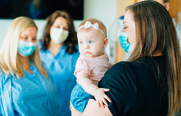 Nurses gathered around baby girl in mom's arms