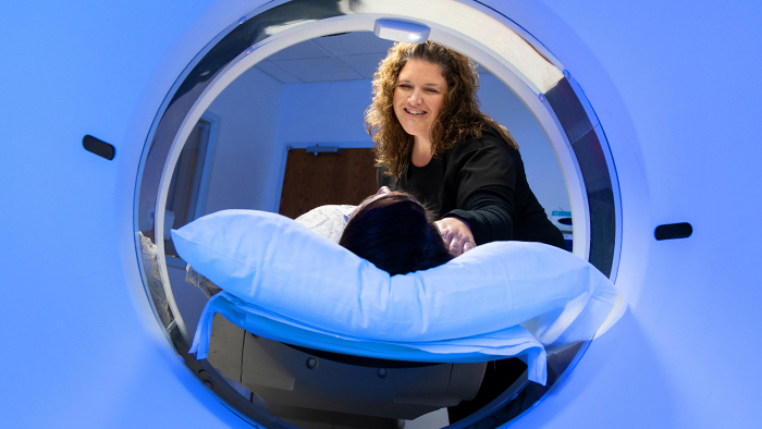 Patient in CT scanner with technician assisting