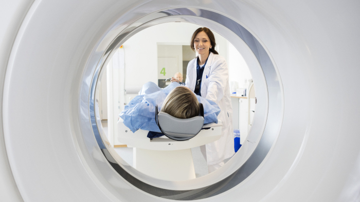 Patient in an MRI machine with technician looking on
