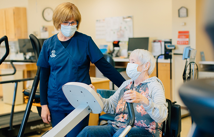 Female nurse encouraging a senior female on stationary bike