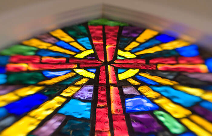 Looking up at a stained glass cross with vibrant colors