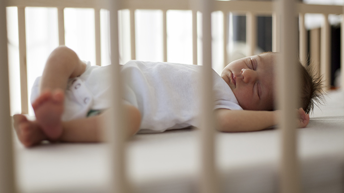 Infant baby sleeping face up in a crib