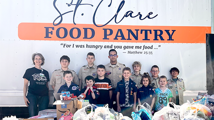 Food pantry volunteers from a boy scout troop standing next to a truck.