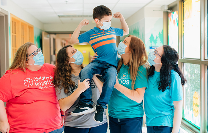 Young boy patient flexing muscles on shoulders of nursing staff