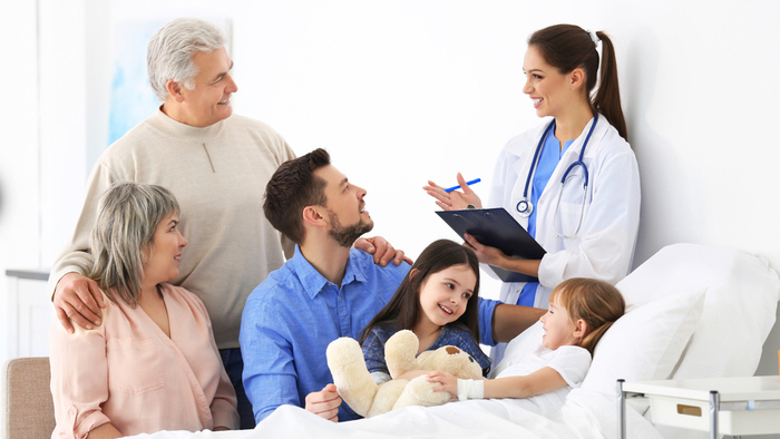 Family surrounding young child in hospital bed