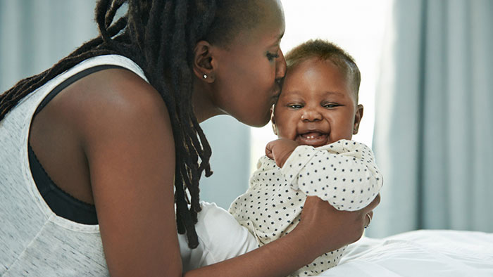 New mom with baby in her arms giving him a kiss