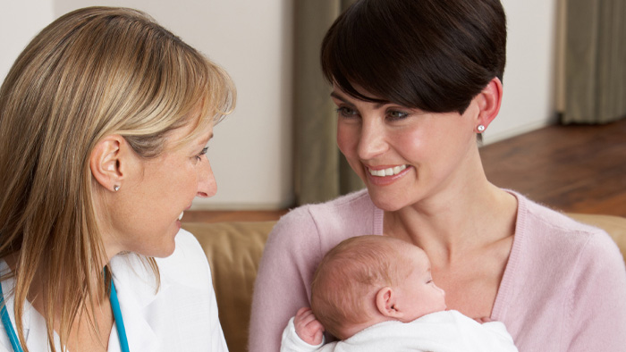 New mom with baby sitting with nurse