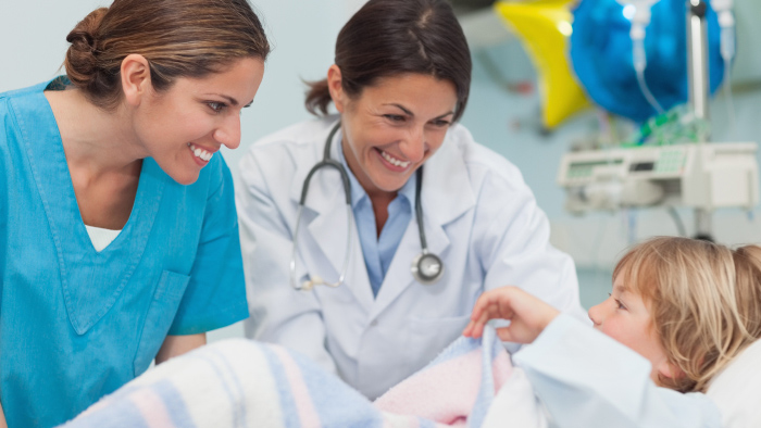 Two women health care professionals talking with a young boy patient
