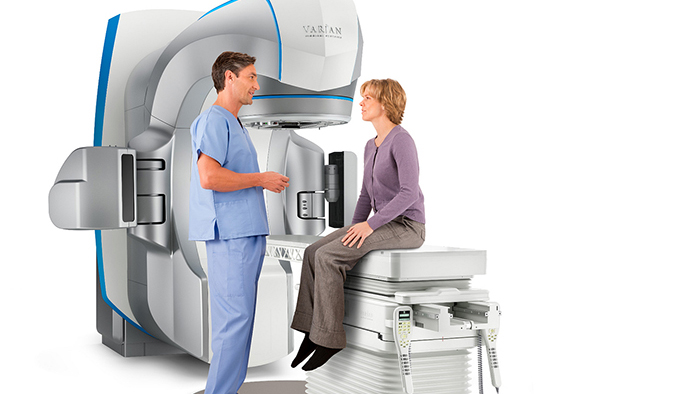 Patient sitting on Varian Edge radiosurgery system as doctor explains procedure