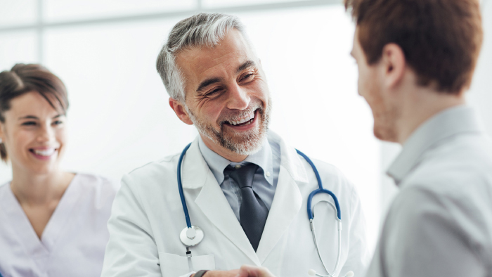 Male physician shaking hand with young man