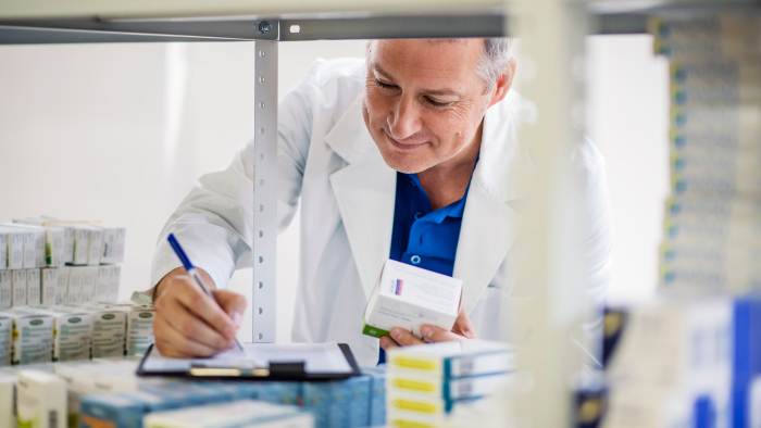 Male pharmacist checking medicine label