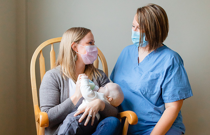 Female nurse encouraging a new mom with baby in her arms