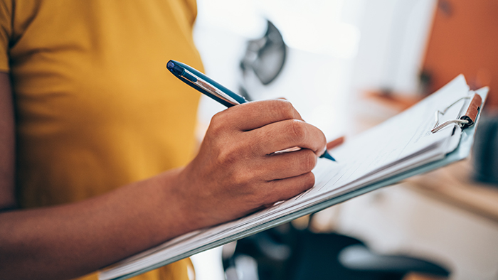 Woman with pen in hand checking off items on a clipboard
