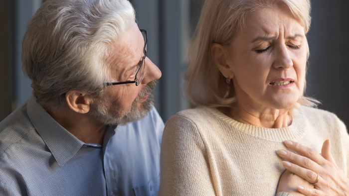 Senior woman experience heart attack symptoms with husband looking on