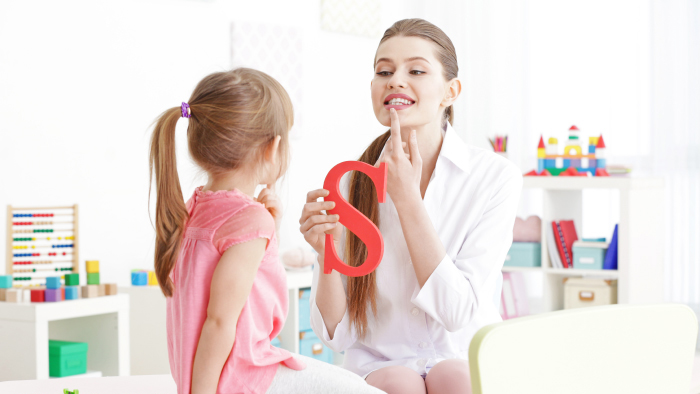Female therapist assisting young girl with speech therapy