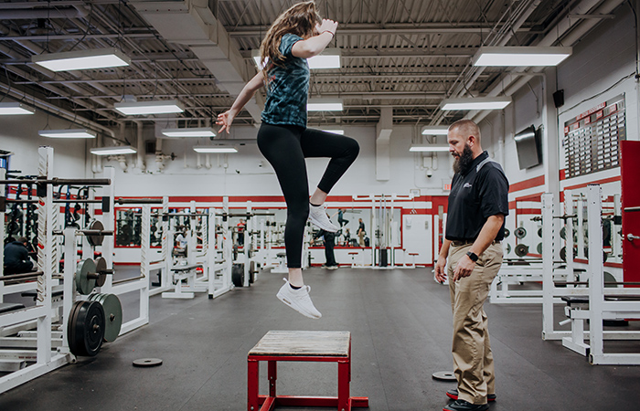 A trainer works with a patient doing box jumps