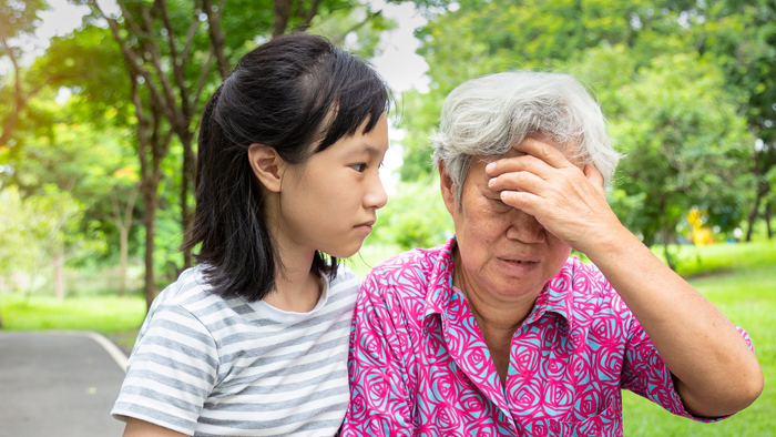 A young granddaughter is helps her grandmother grasping her head during a stroke 