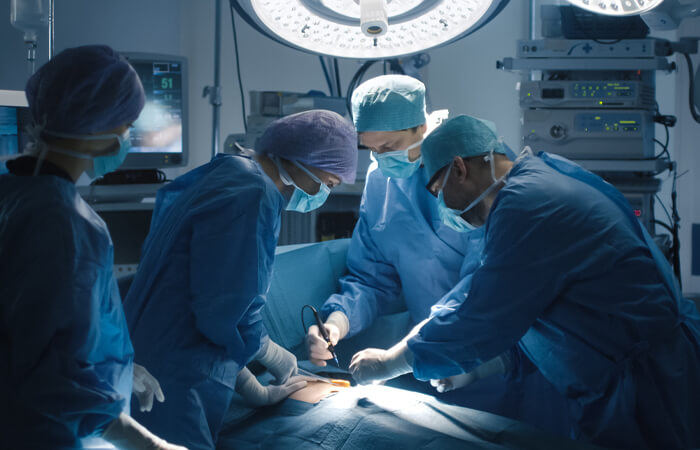 Operating room with four a surgeon and his surgical staff prepping the patient on the operating table