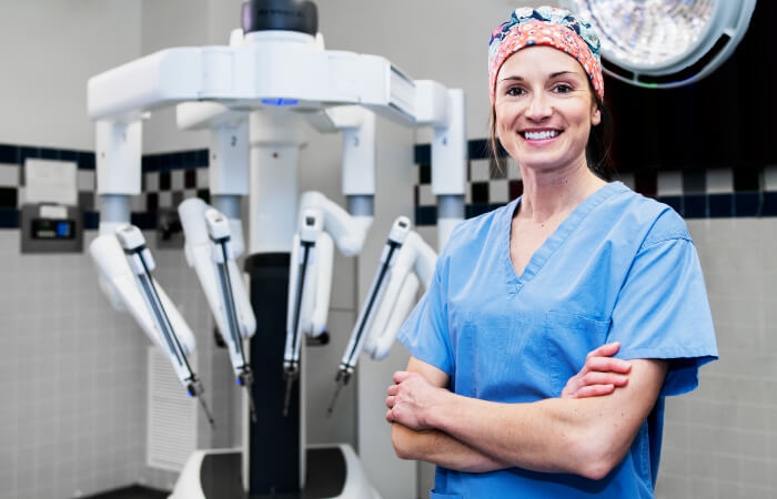 Nurse posing in front of surgical robot