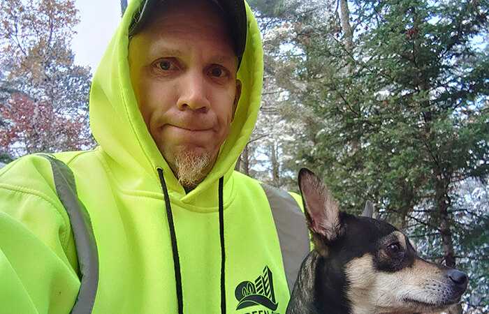 Brent wearing a bright green sweatshirt standing outside with his pet dog