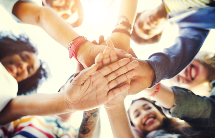 A group of diverse adults put their hands in a circle