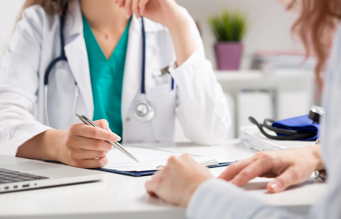 Mature Male doctor and middle aged female doctor shaking hand with male patient