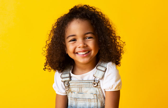 smiling black little girl on bright yellow background