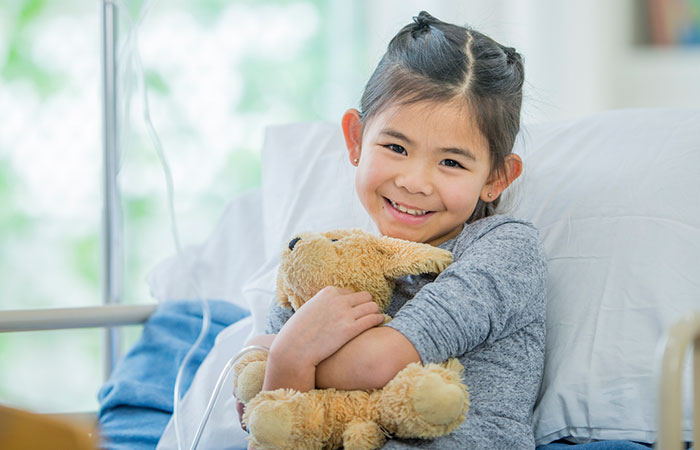Girl with stuffed animal in hospital bed