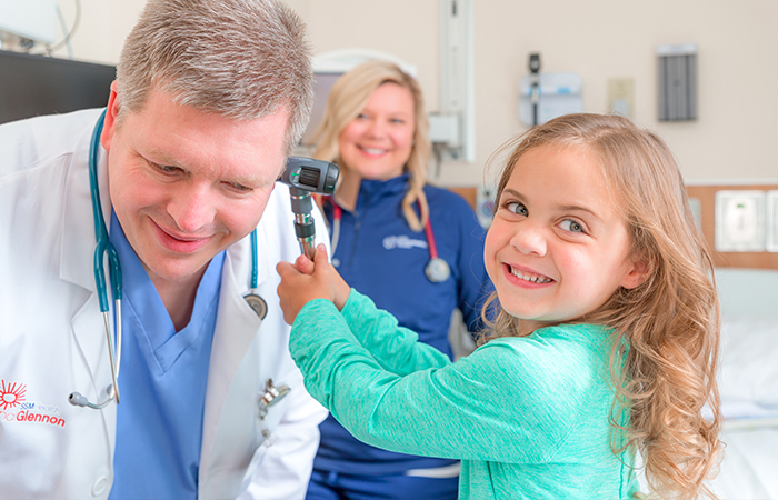 St. Joe's Highland - young girl giving doctor an ear exam and smiling