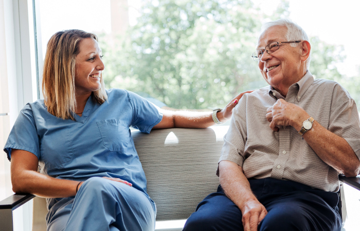St. Joseph Highland - nurse and elderly man sitting on couch smiling and laughing