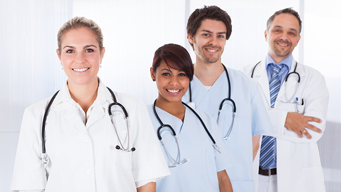 Nurse, caregiver, technician and doctor standing in group