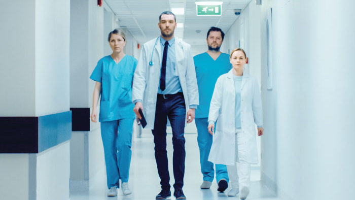 Team of four doctors walk down a hallway